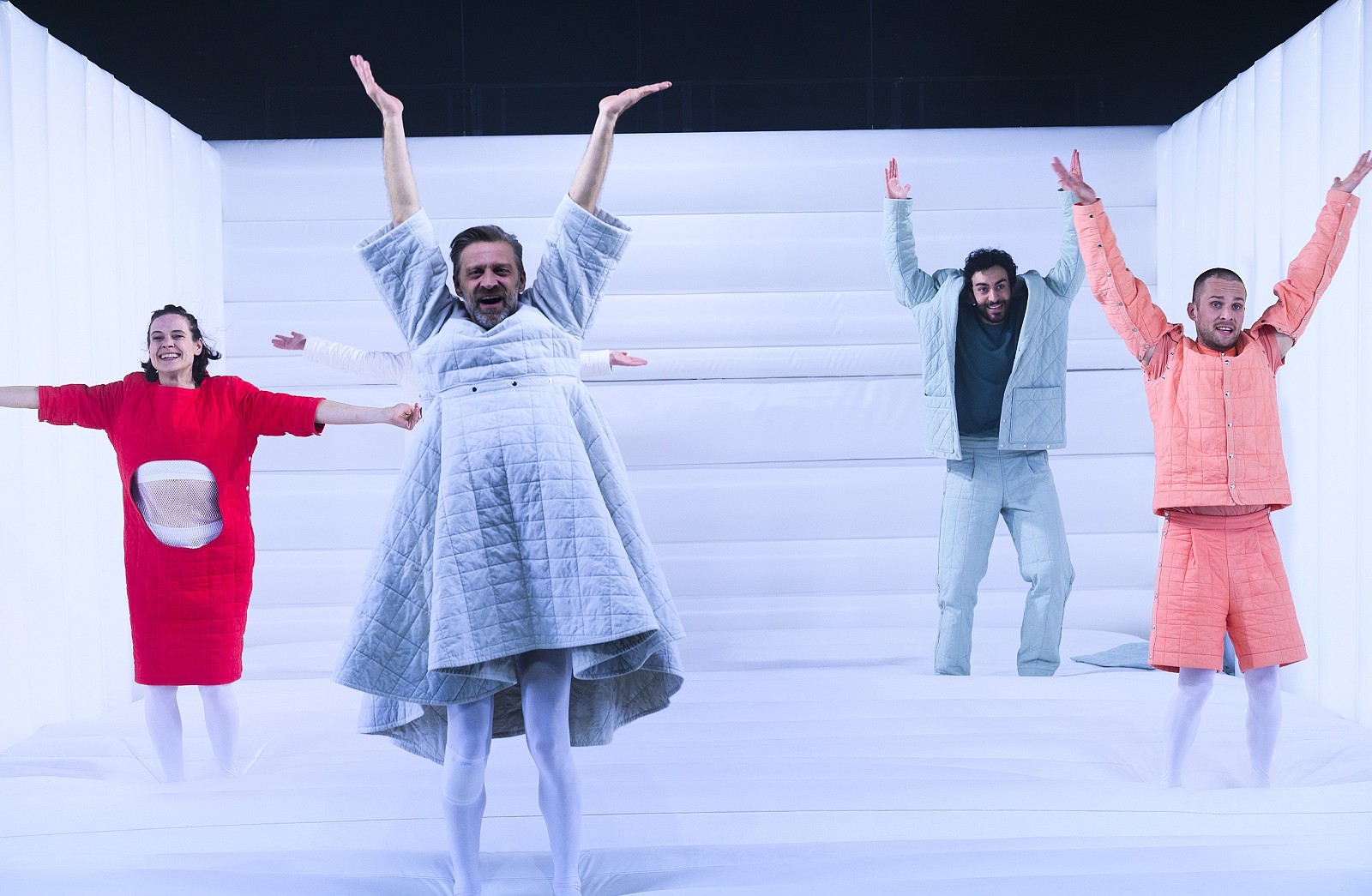 Vier Schauspieler*innen in Steppjacken heben die Arme
