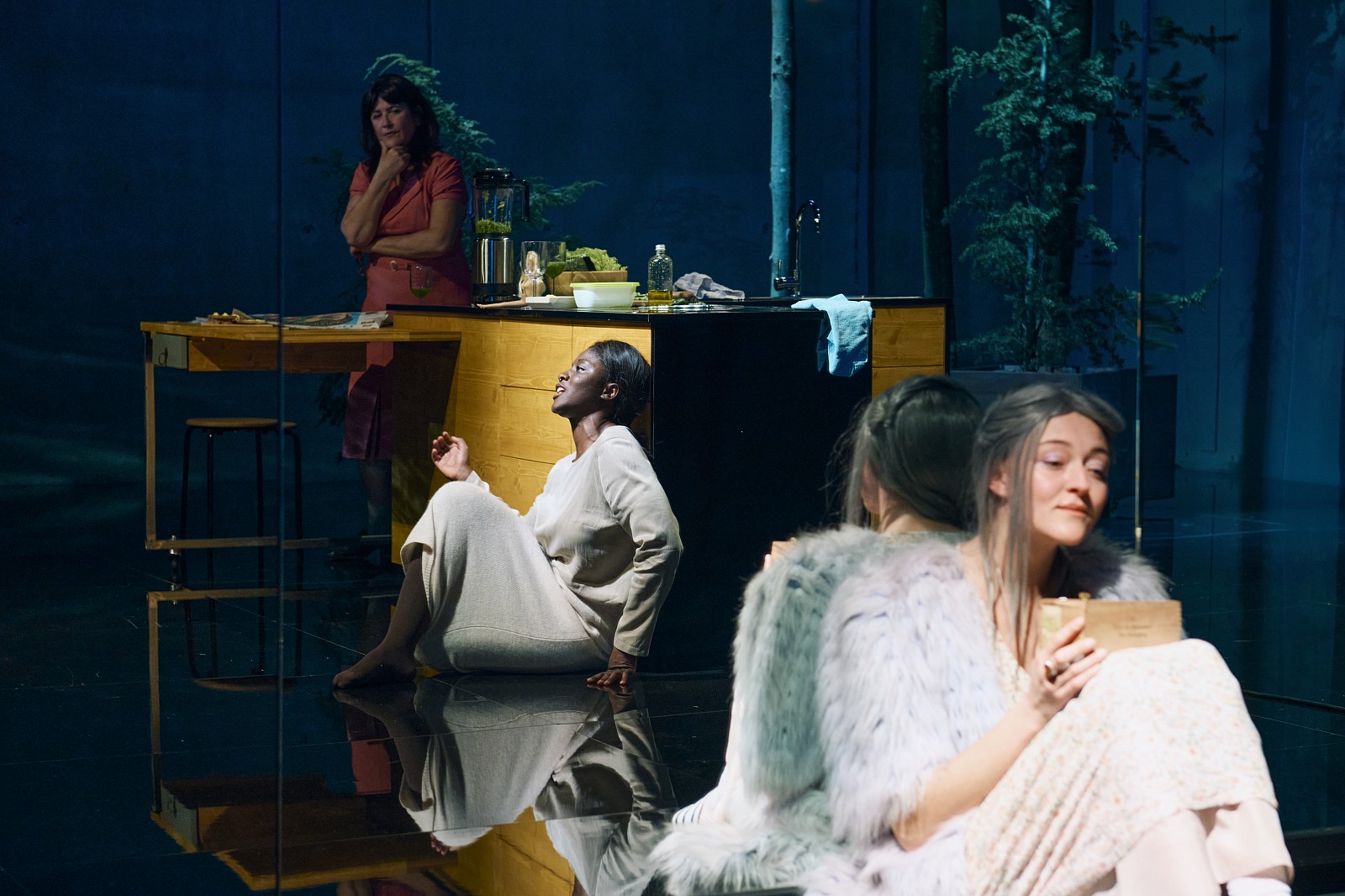 Woman sits on the floor, behind her a mirror, on the stage it is dark